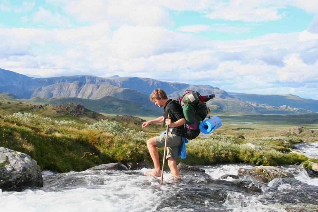 Wandelaar steekt rivier over in Jotunheimen